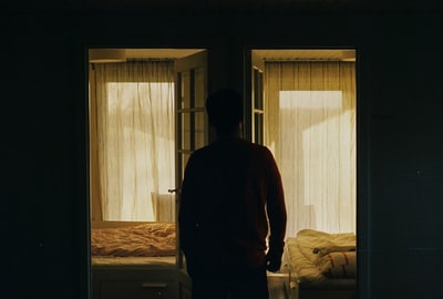 站在窗边的穿红色长袖衬衫的男人